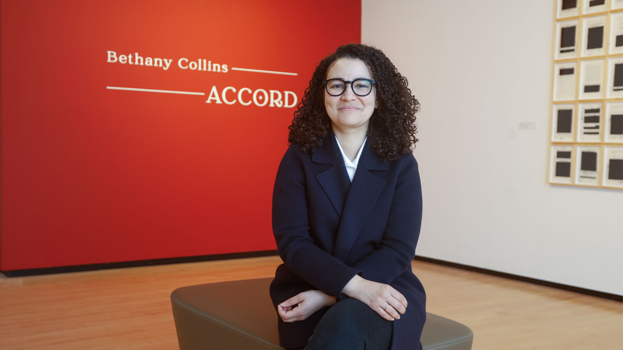 Artist Bethany Collins sits in front her artwork in the exhibition, "Accord."