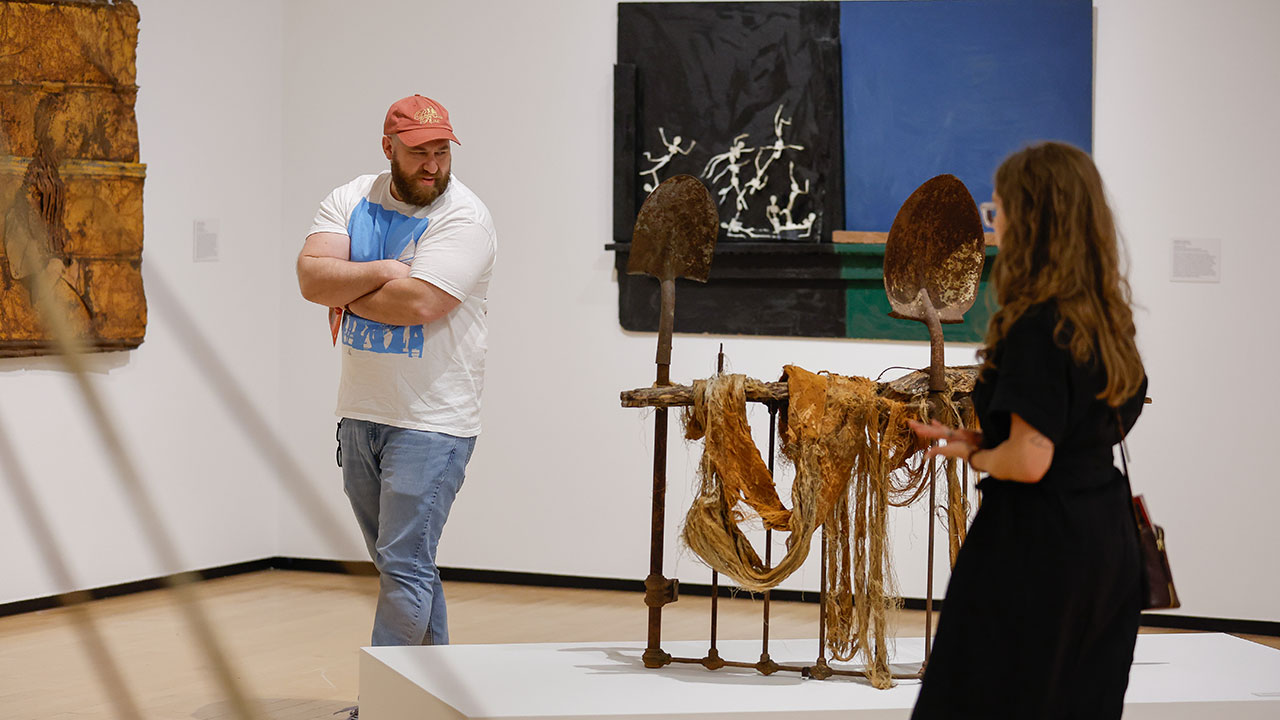 Visitors at The Jule Museum examine Three Shovels to Bury You by artist Lonnie Holley in The Jule Museum's Black Codes exhibition.
