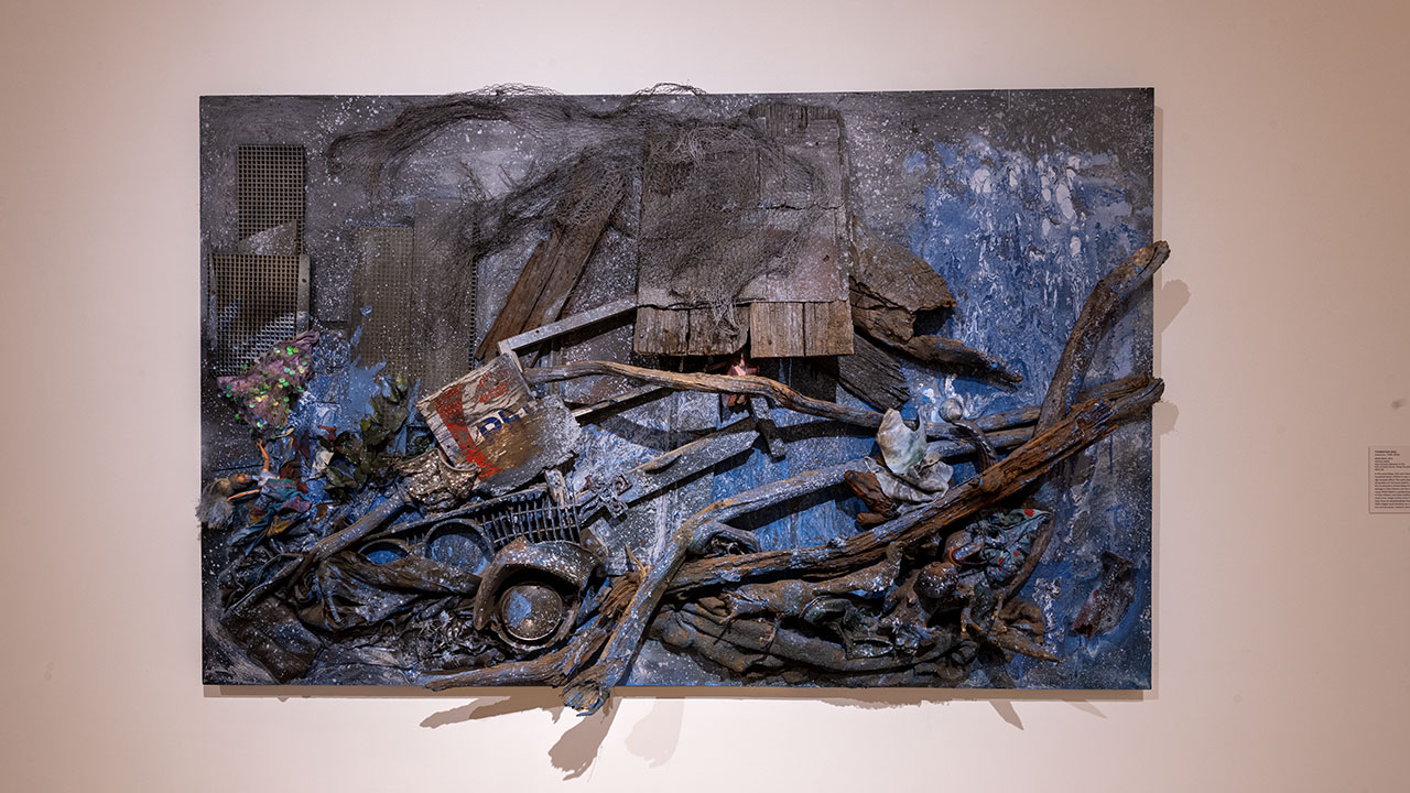 Ninth Ward, 2011, Thornton Dial, courtesy of the New Orleans Museum of Art. Canvas featuring found materials such as driftwood, toys and clothing, splattered with blue and white paint, evoking feelings of submersion.