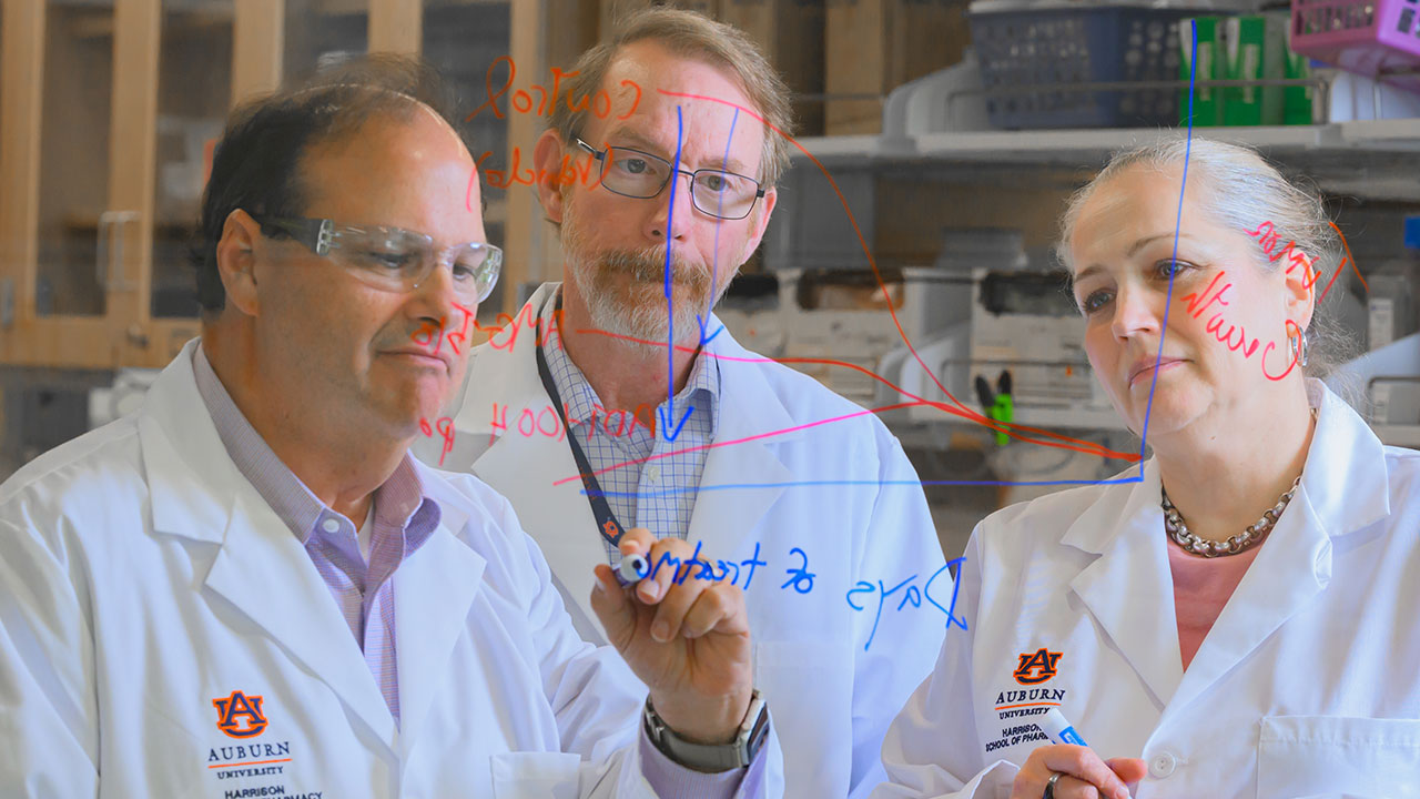 Gary Piazza and his colleagues write out a problem on a glass wall
