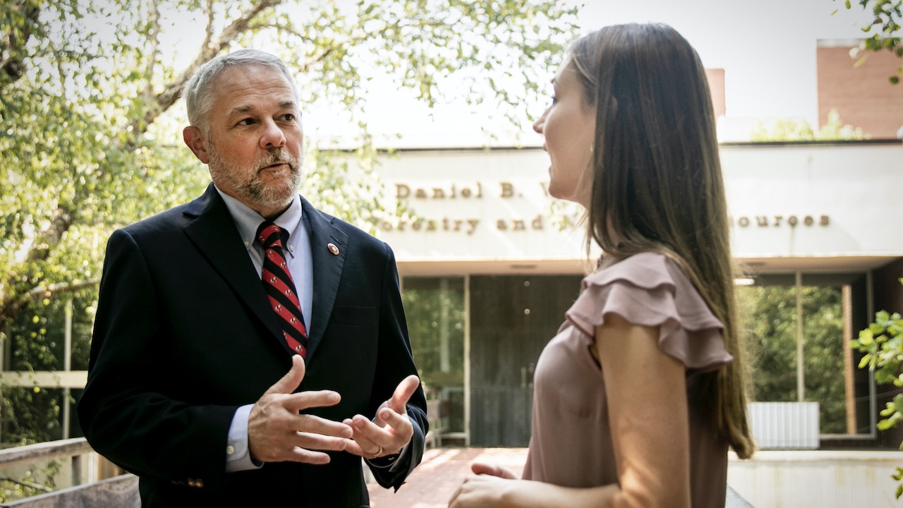 Man talking with young woman outside in front of building