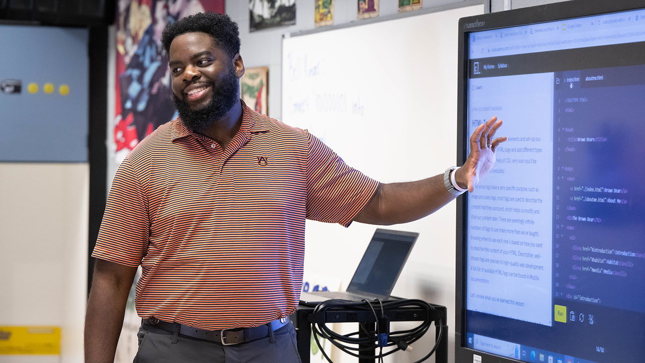 An Auburn University College of Education alumnus stands in front of his class teaching.