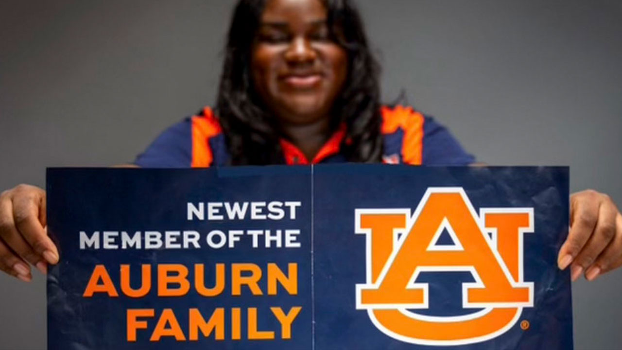 A student is pictured holding an Auburn banner.