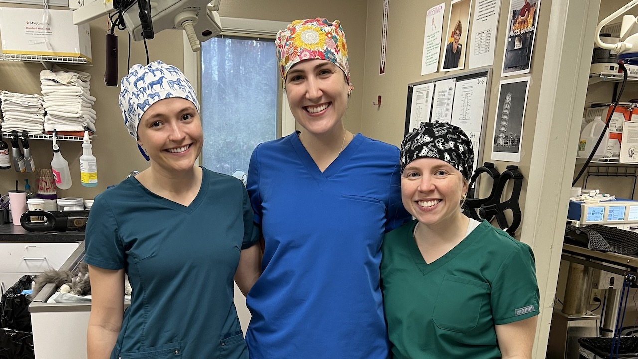 Three female students in scrubs pose for a picture in the surgery room.