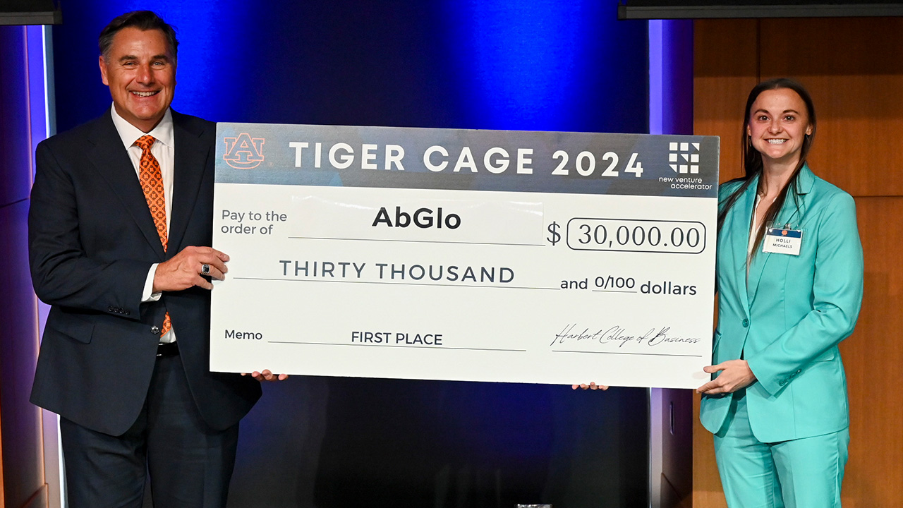 A man and a young woman hold a large check made out for 30,000 dollars