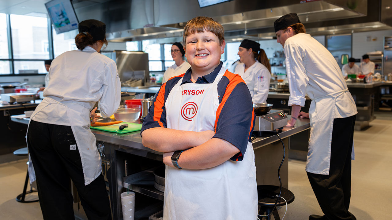 Bryson McGlynn stands in front of students cooking