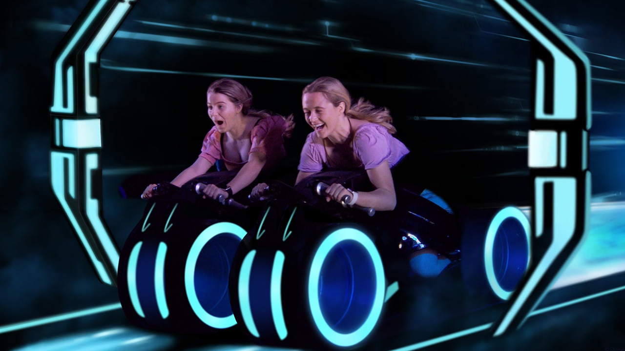 Two young women scream with joy as they ride on neon bikes through a dark tunnel
