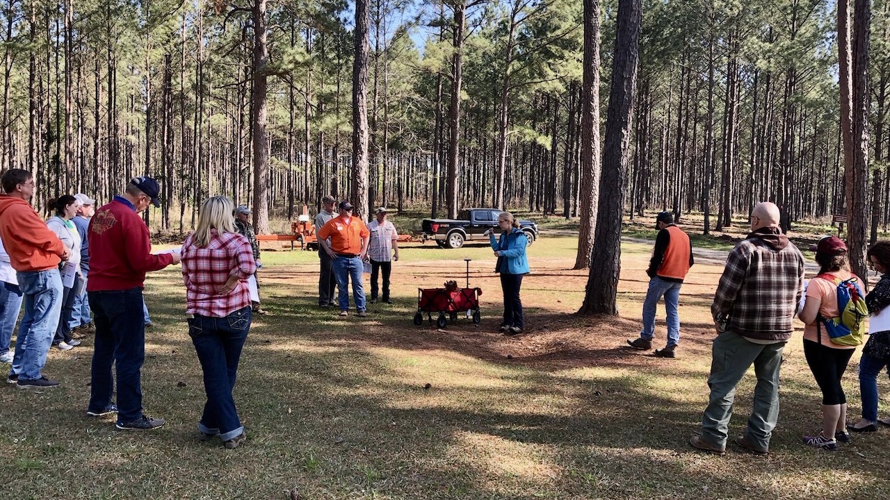 Circle of people outside in forest listening to one person speak