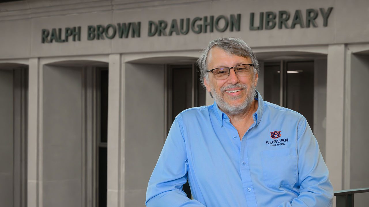 Jayson Hill stands in front of the Ralph Brown Draughon Library sign