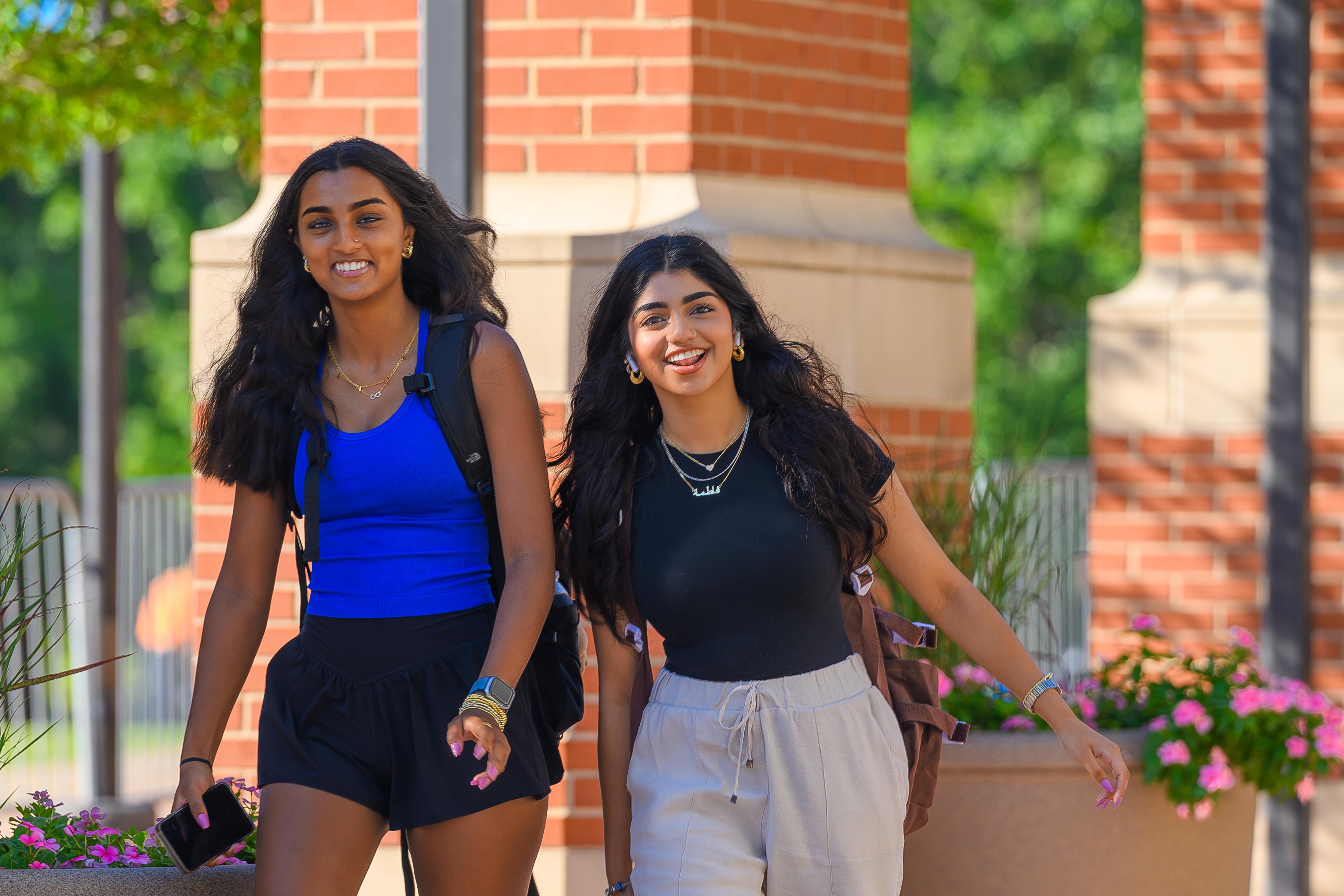 Students walk whie smiling on campus.