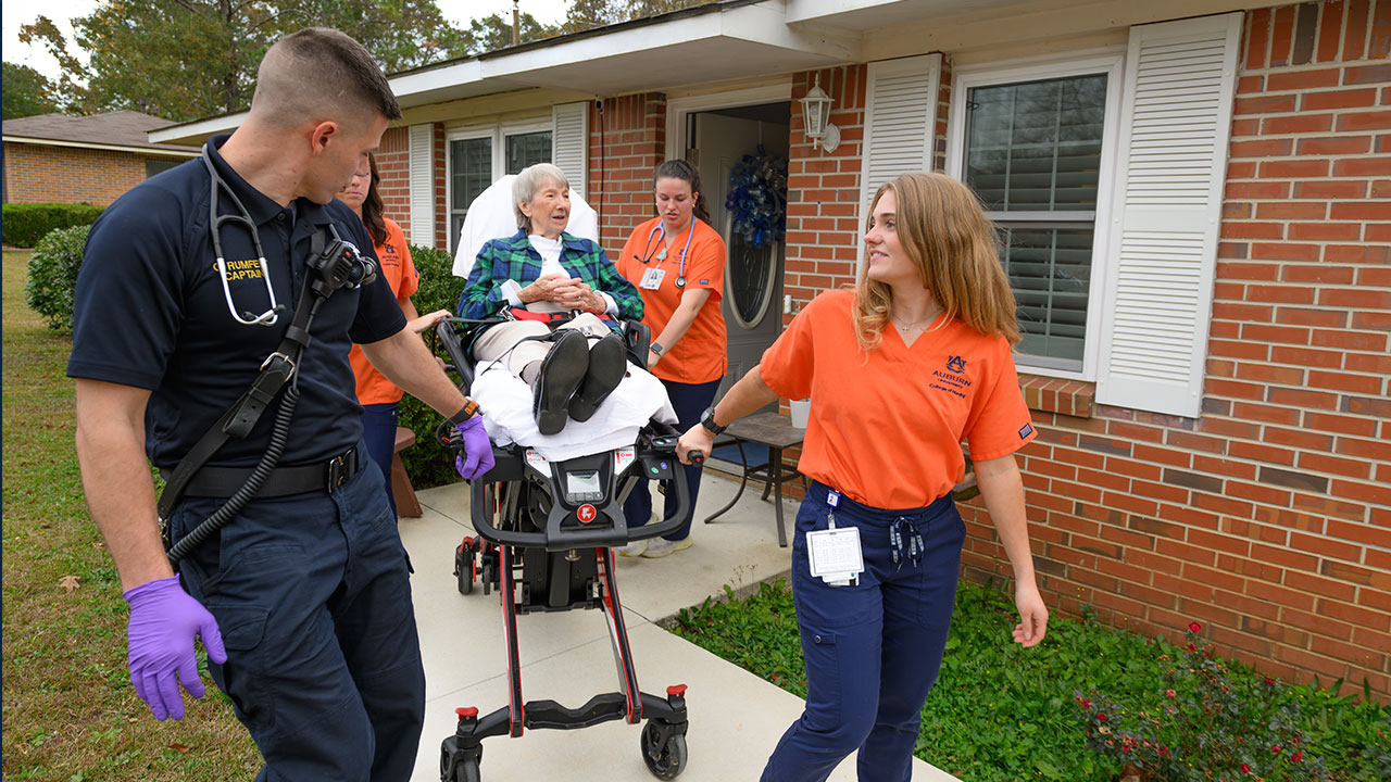 Nursing students and Chambers County EMS help a patient from her home