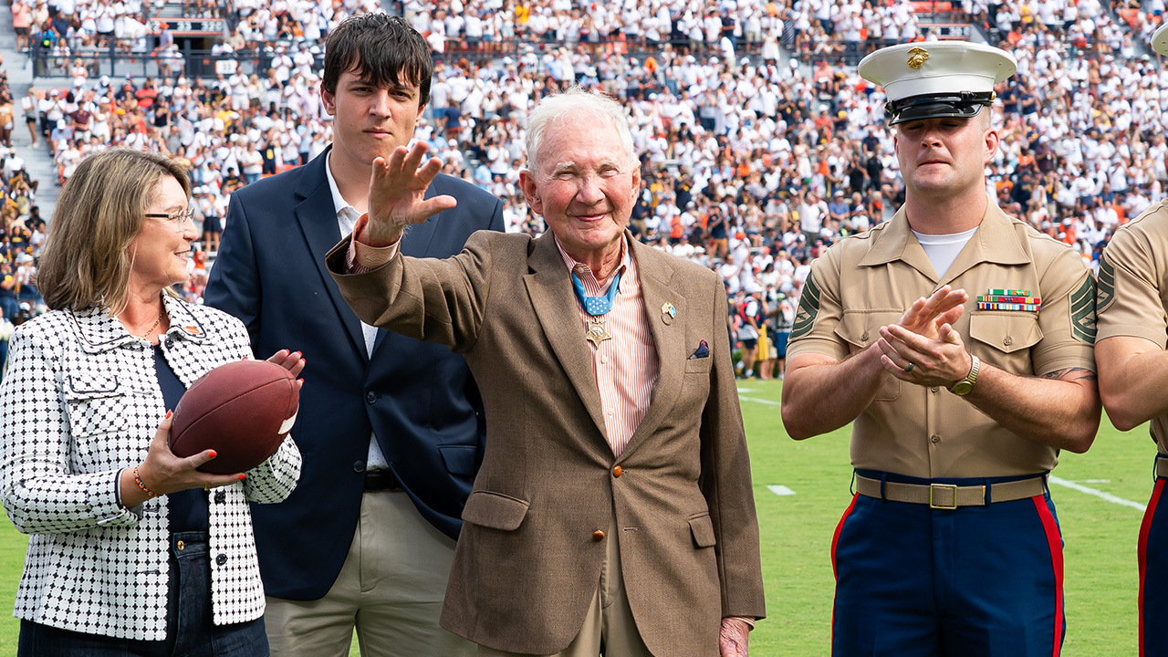 Major General Livingston smiles and waves to the crowd in a footballs stadium