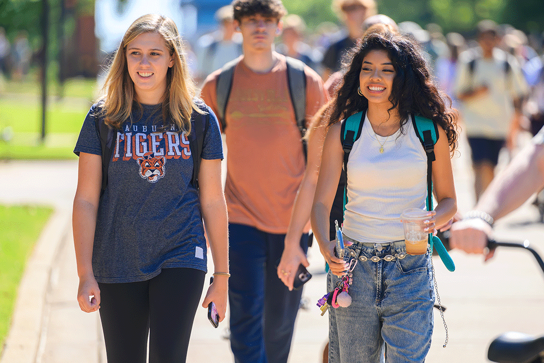 Auburn students are walking on the concourse smiling.