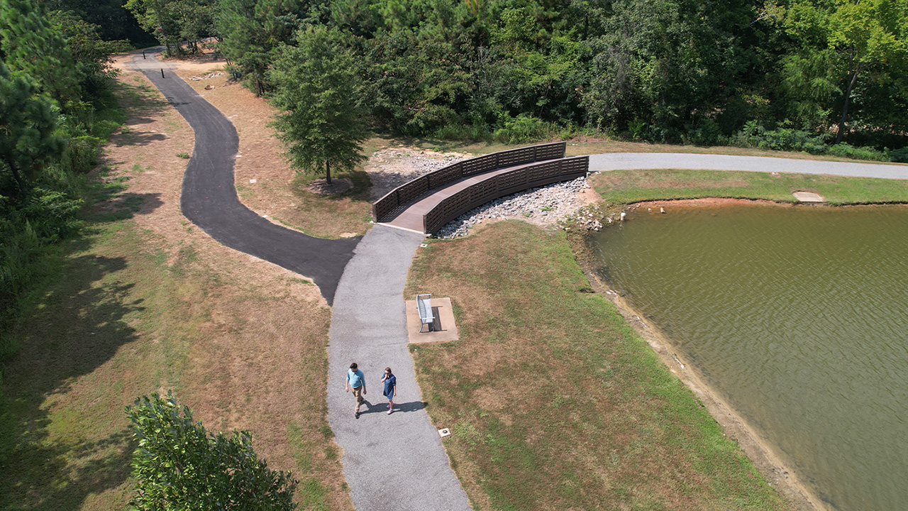 Two people walk alongside a lake