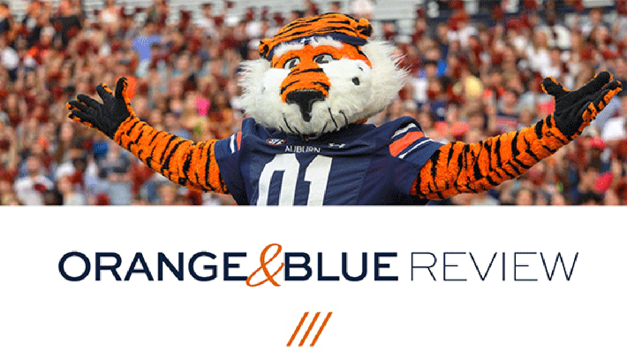 Aubie hold his hands out above the words Orange and Blue Review.