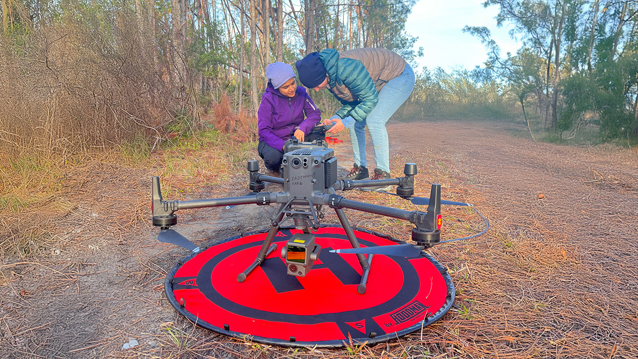 Two people work on a drone in a forest