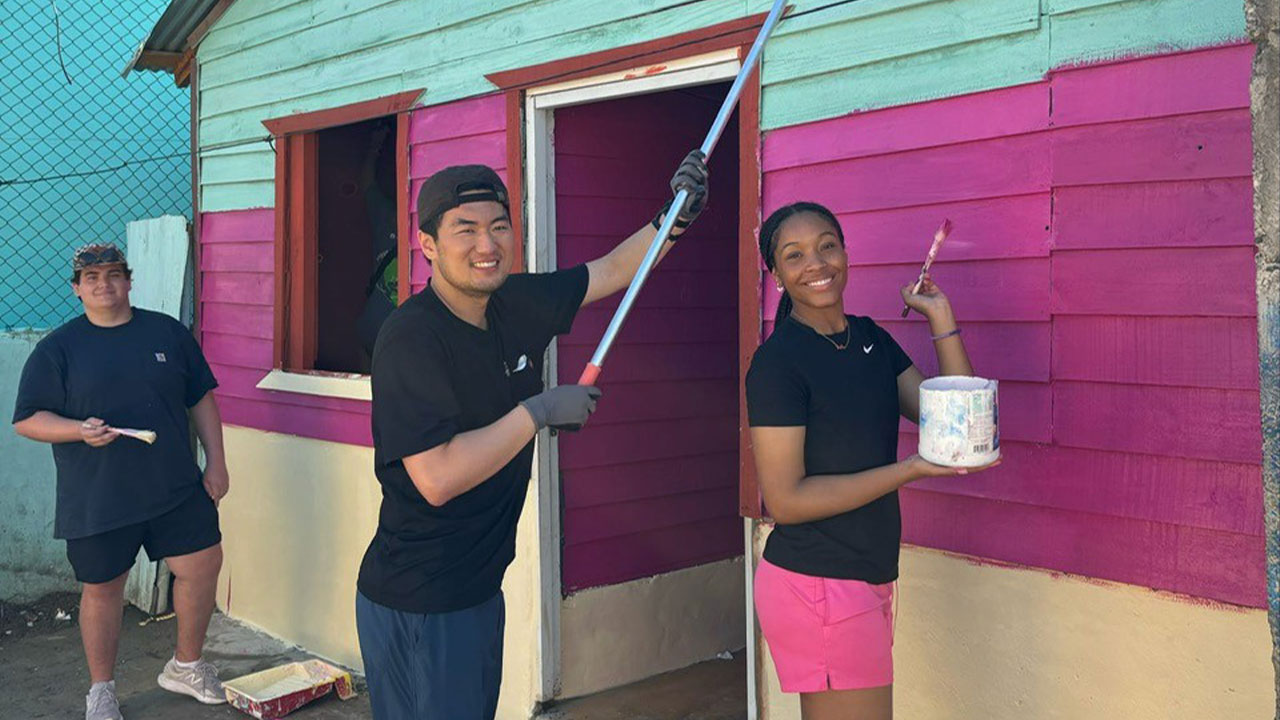 three students painting a building