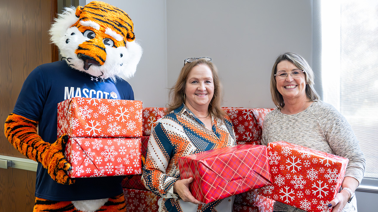 Aubie, Denise McNutt and First Lady Mrs. Roberts hold wrapped packages