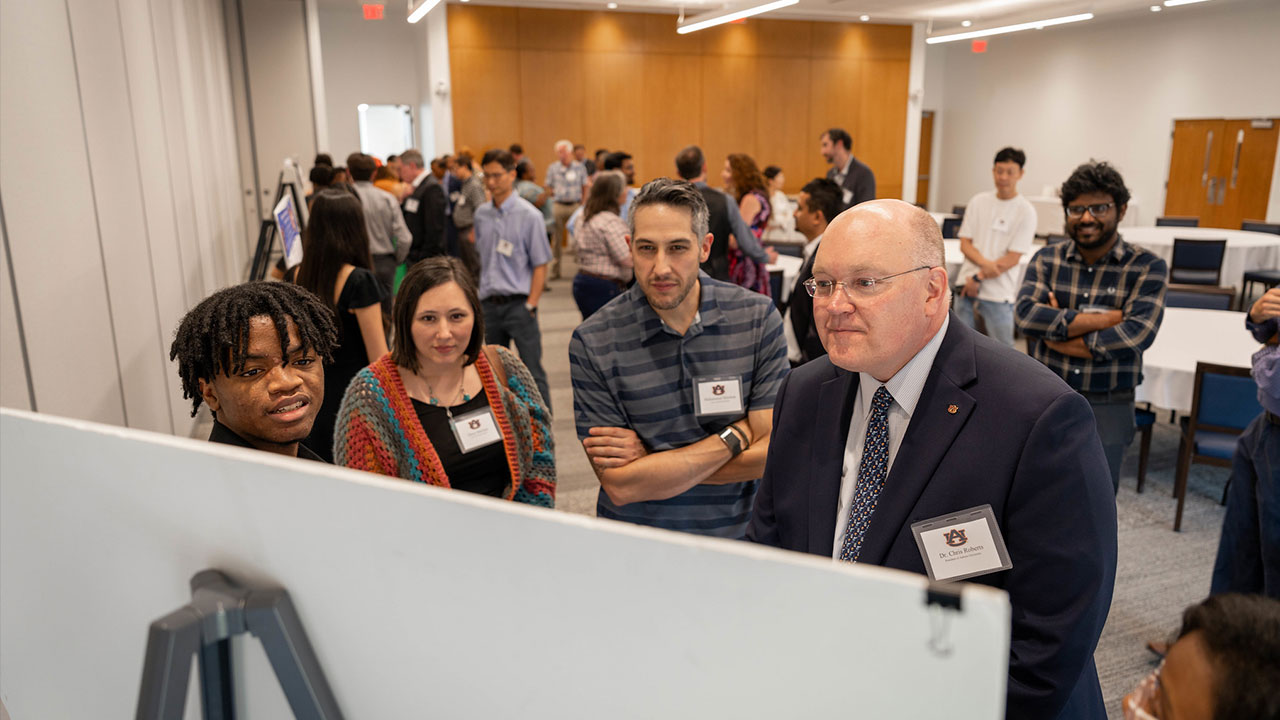 President Christopher B. Roberts and others look at student research