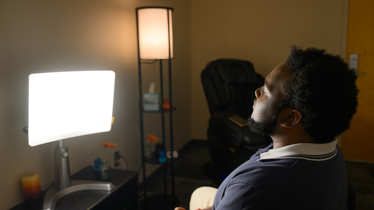 A young man sits in front of a bright light