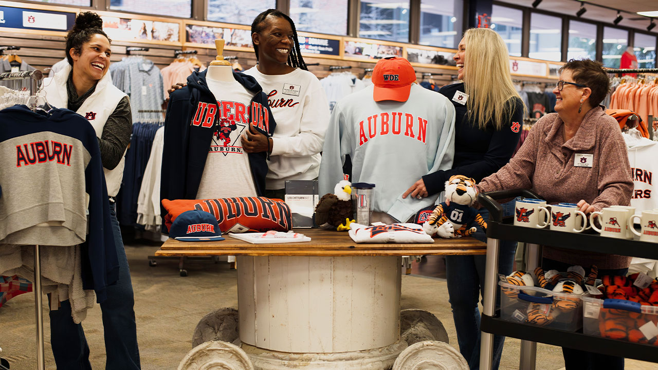 four ladies put Auburn gear and items in place in the AU Bookstore
