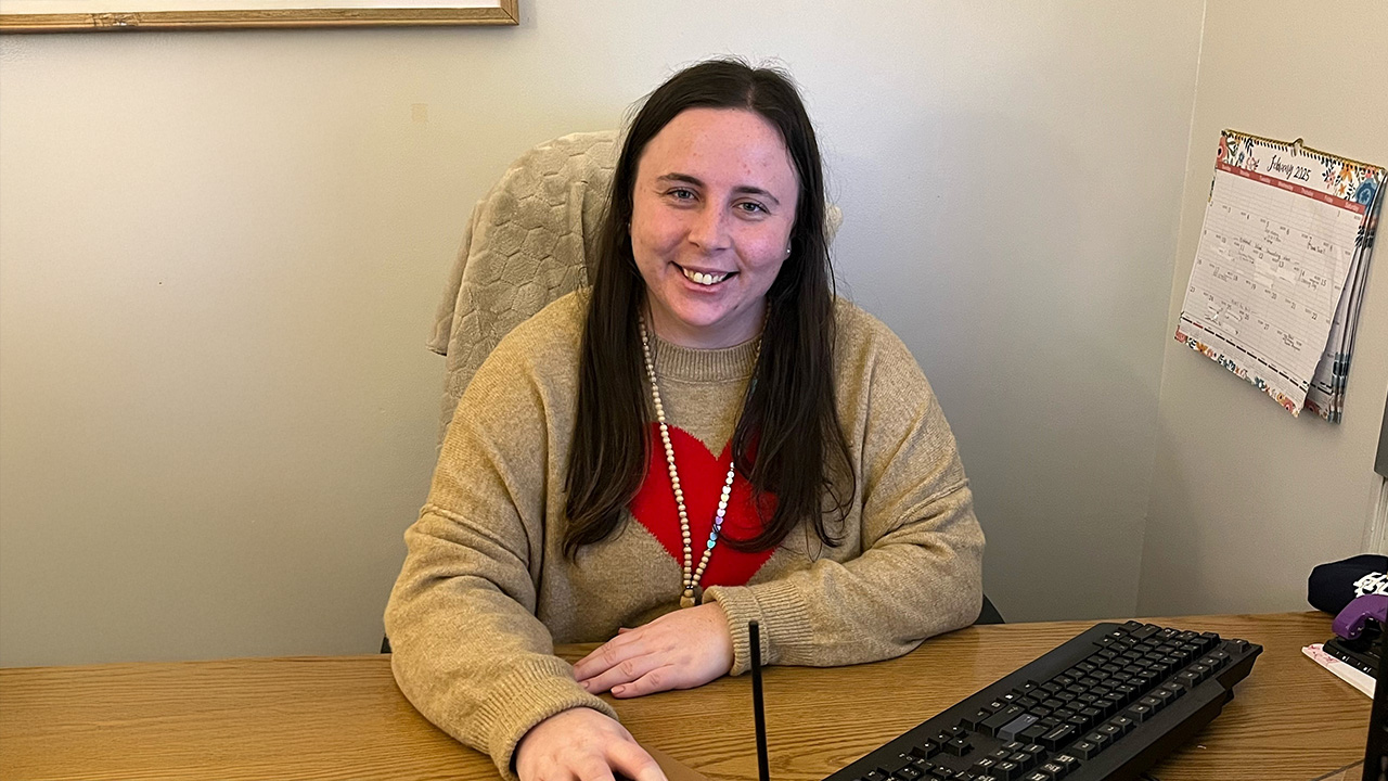 Lauren sits at her desk in an office