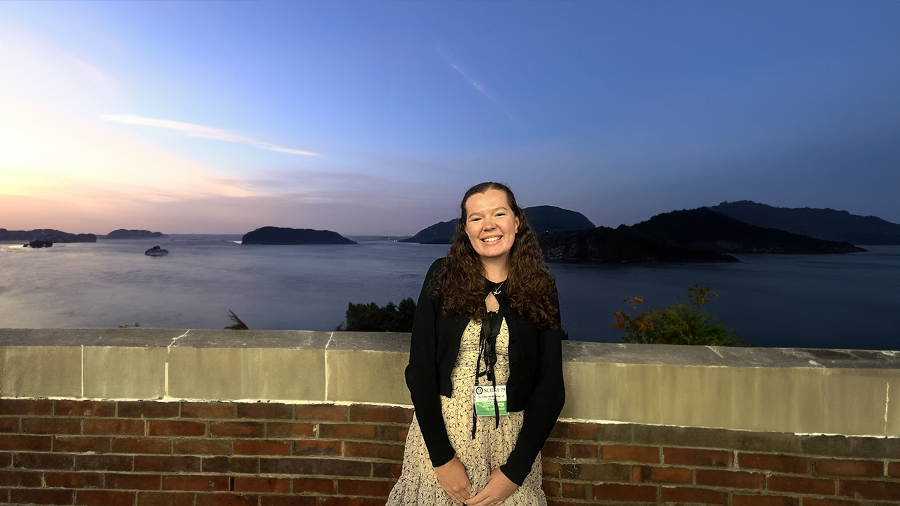 Clara Ragan smiles for a photo with the sunset in the back.