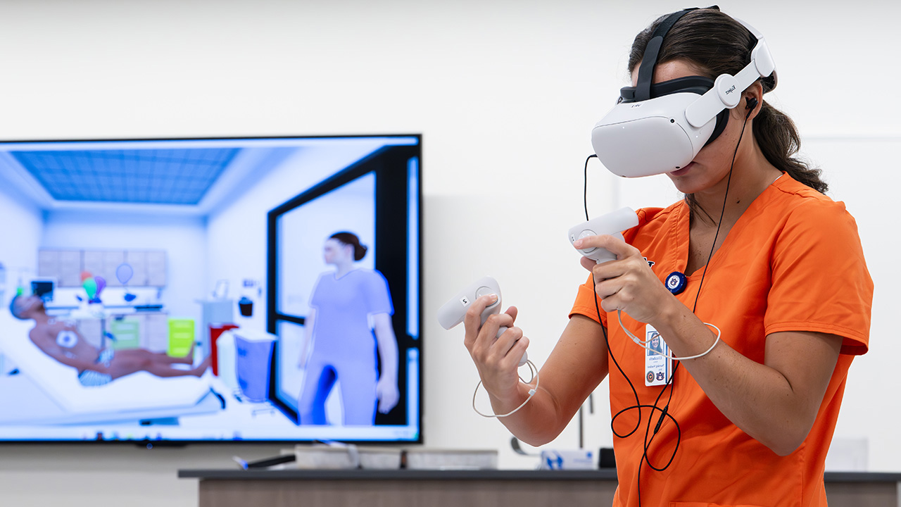 A young woman in a virtual reality headset in front of a computer monitor