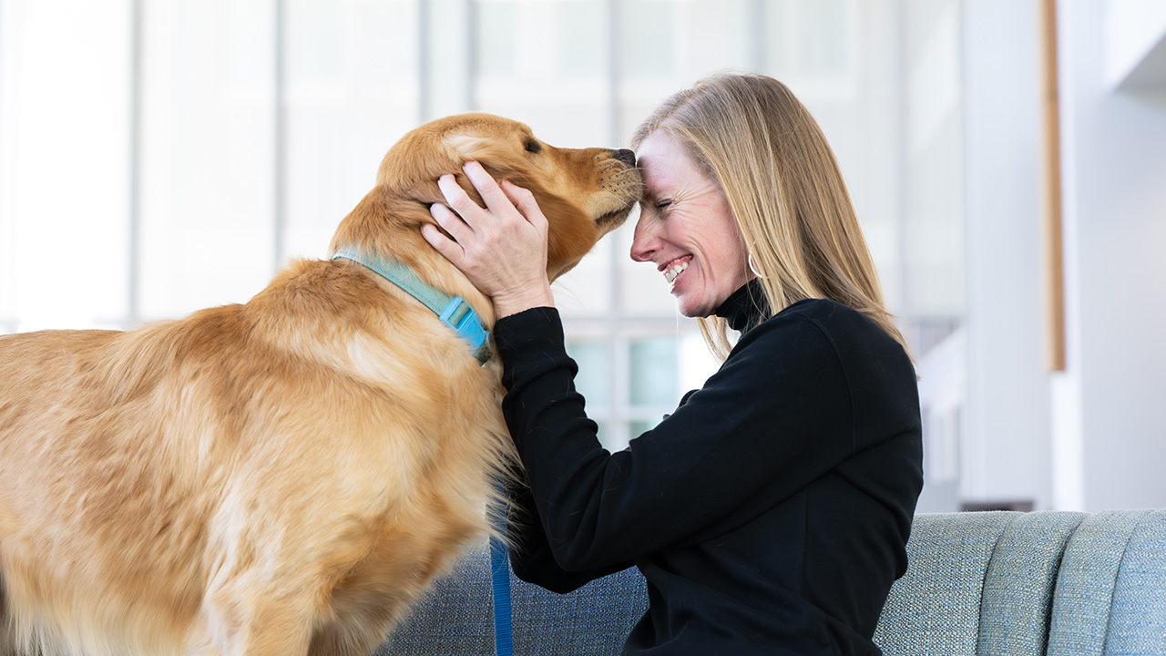 Morgan snuggles with a golden retriever dog