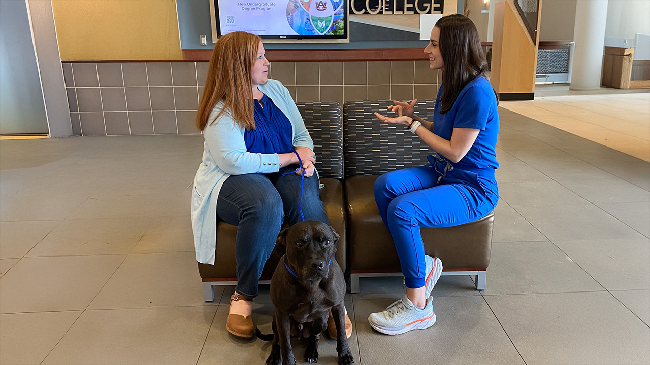 Marissa uses sign language to communicate with a woman who has her dog on a leash