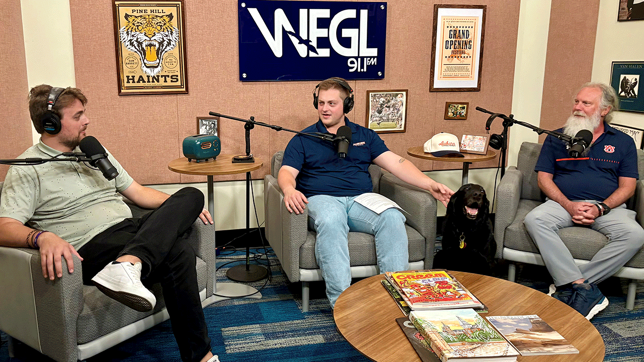 Three men sit in chairs as they talk together on a podcast.