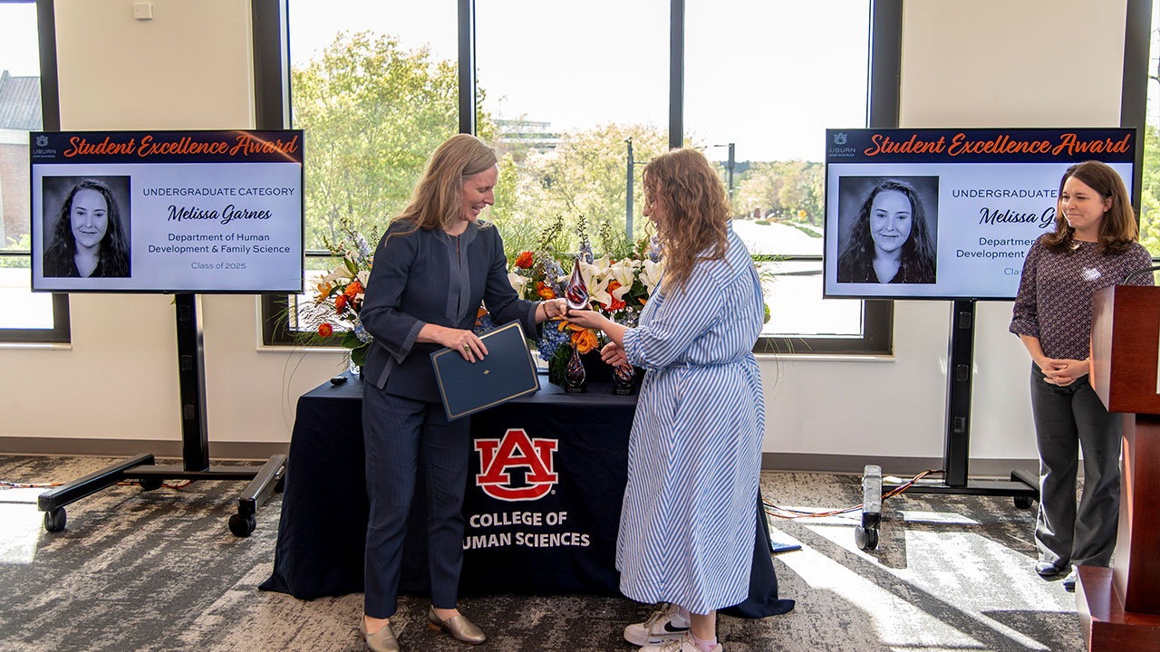 a woman hands a young lady an award