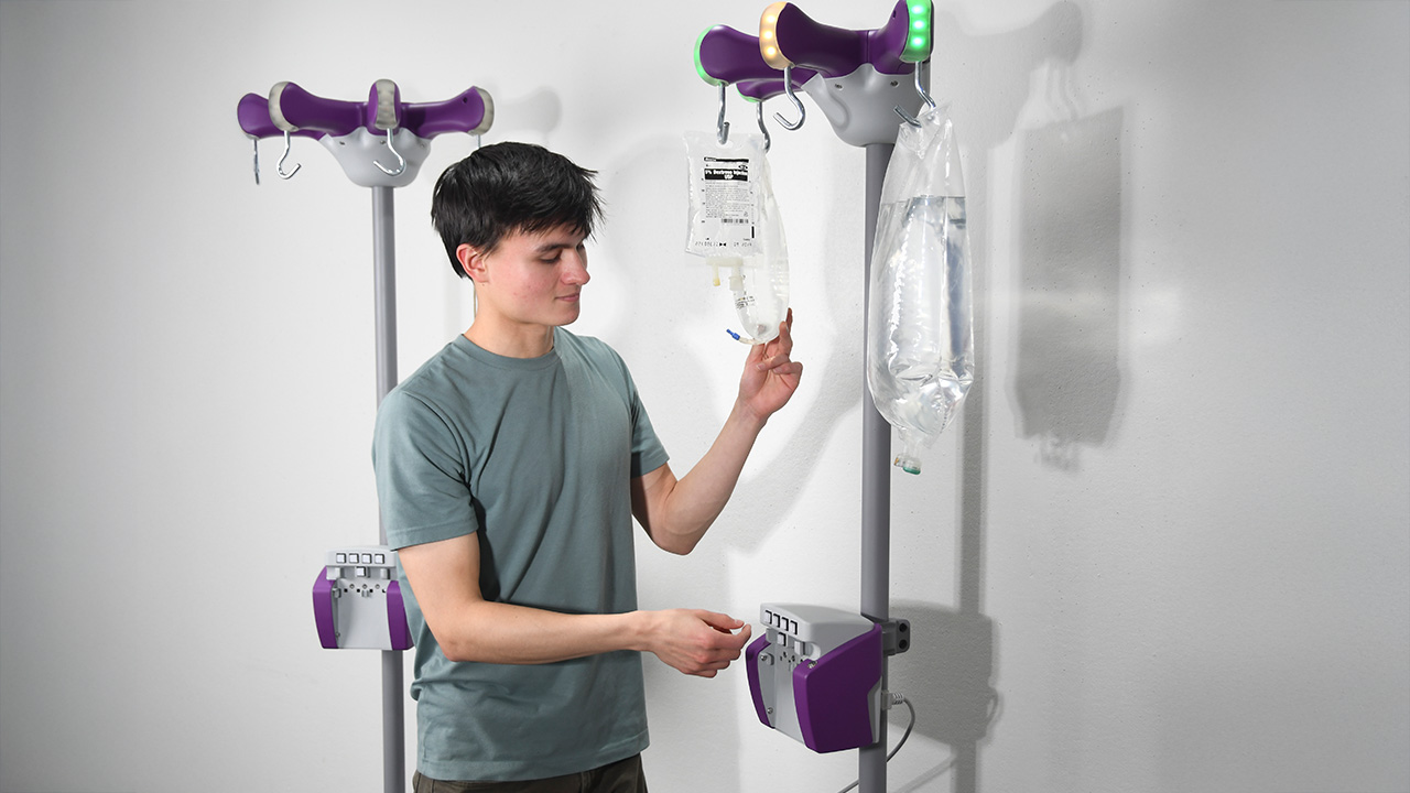 A young man holds an IV pole with lights on top