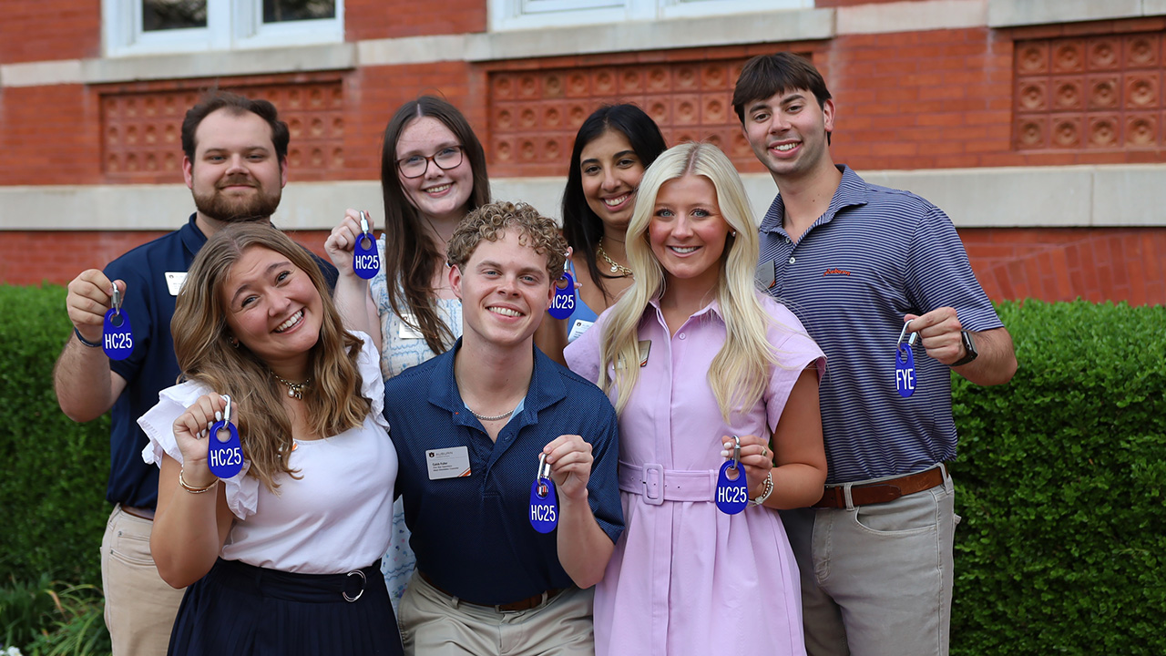 A counselor leads a group of incoming students along a campus sidewalk