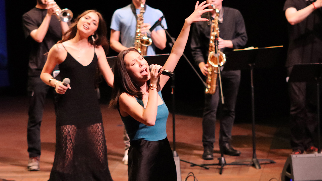 Anna sings into a microphone on stage