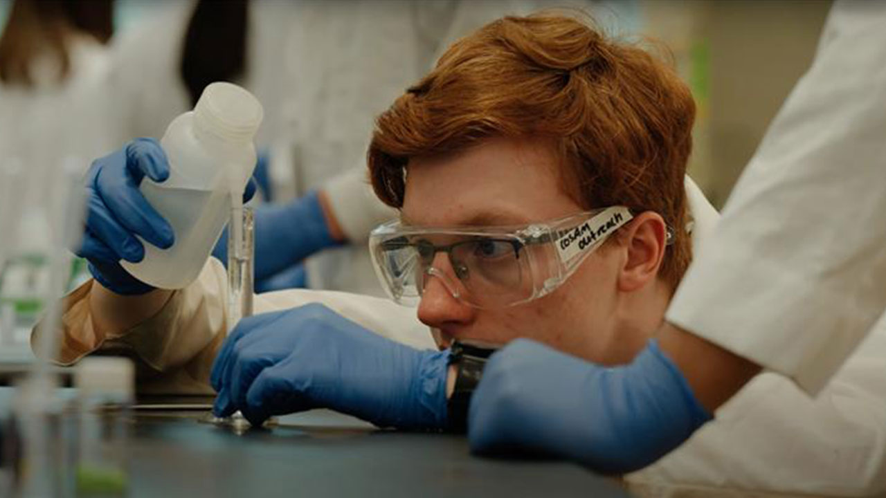 A student looks into a test tube in a lab