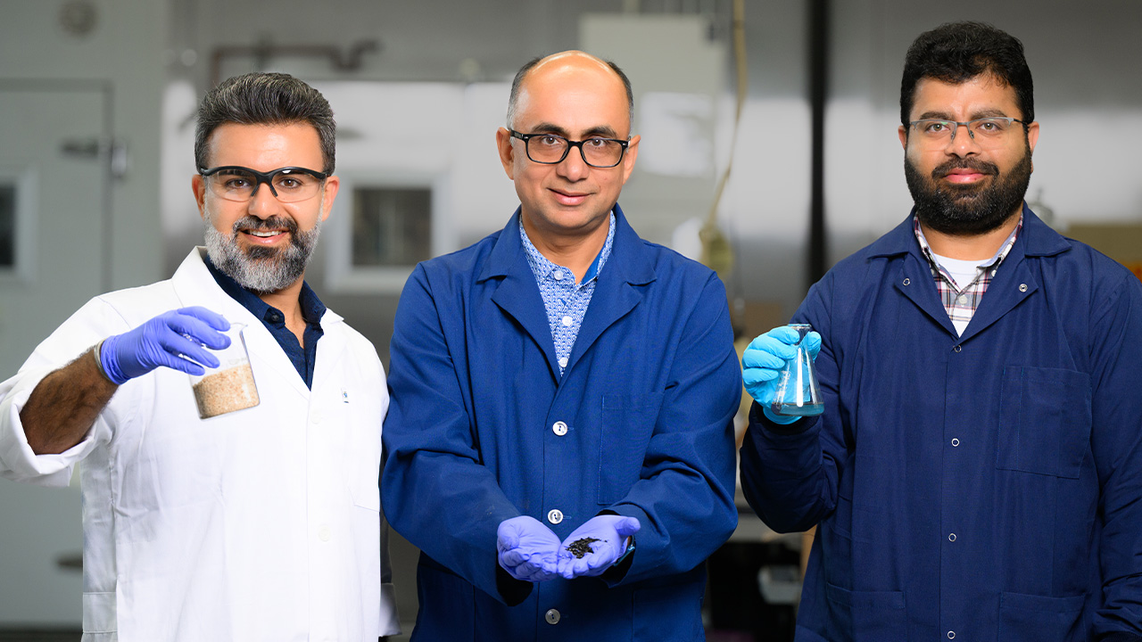 Three men in lab coats hold scientific equipment