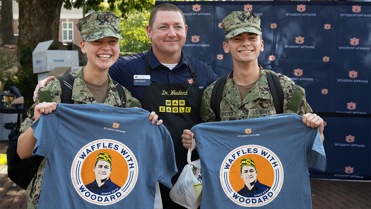college administrator poses with two ROTC students