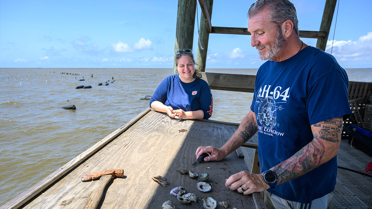 Jill and oyster farmer Hugh McClure examine oysters on a platform over the bay