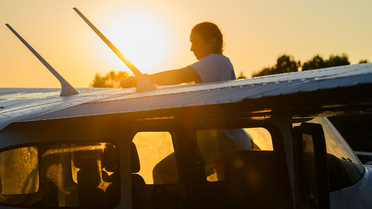 a young woman works on an airplane in the early morning