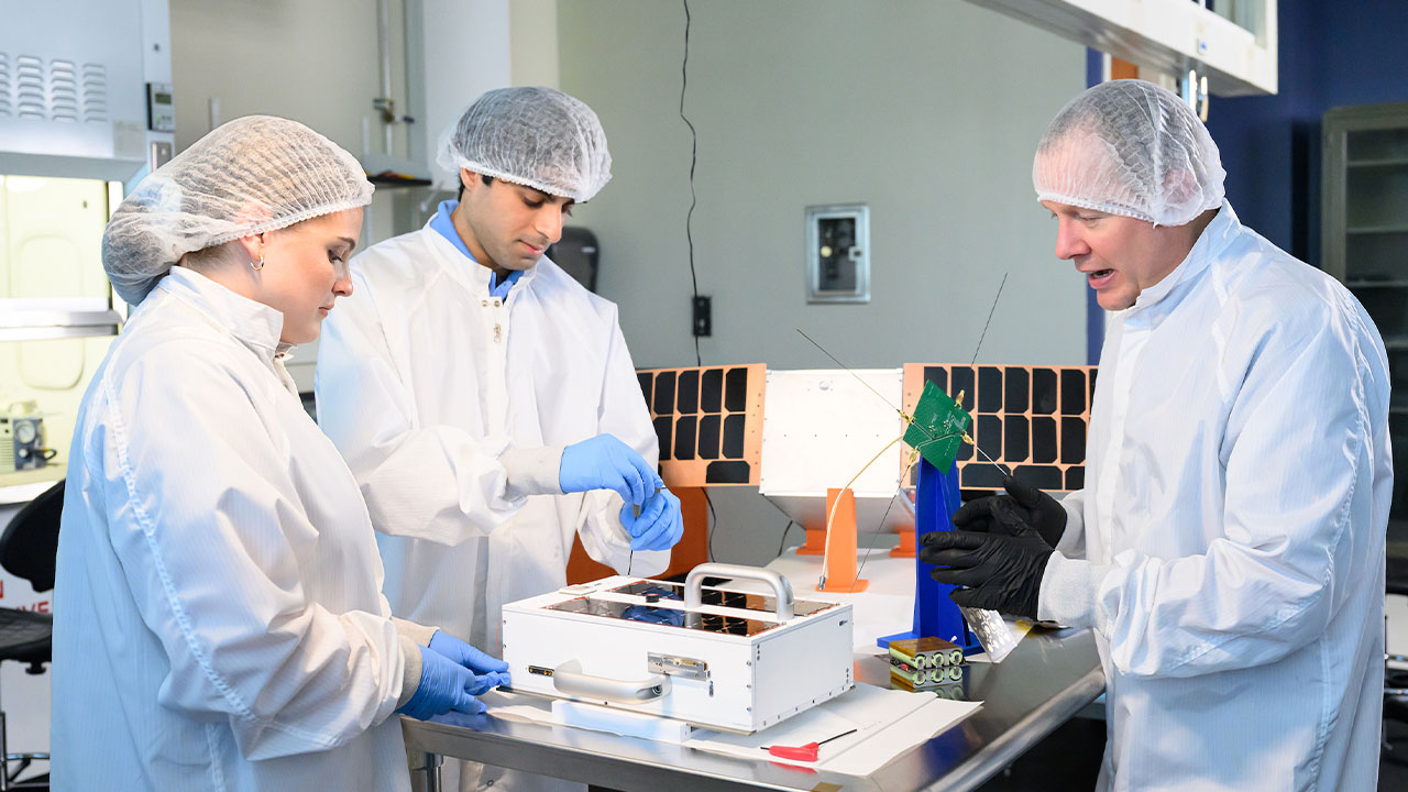 Mark Adams, right, works with two students in the small satellite lab on campus