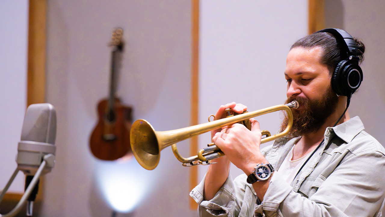 A man plays the trumpet into a microphone