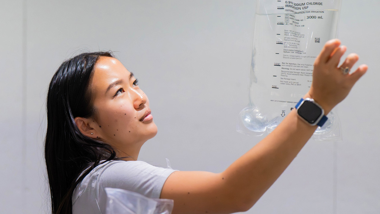 A young woman holds up an IV bag to examine it
