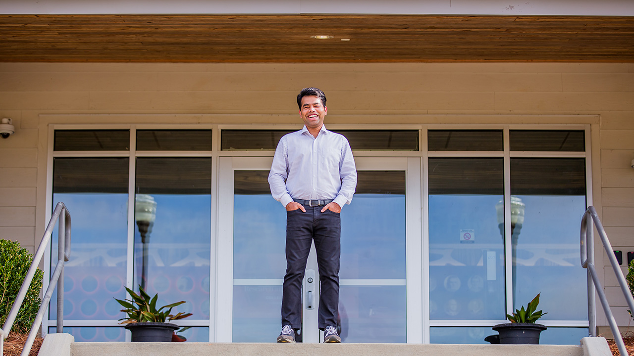 Rana stands on the stairs in front of the door of the poultry science building