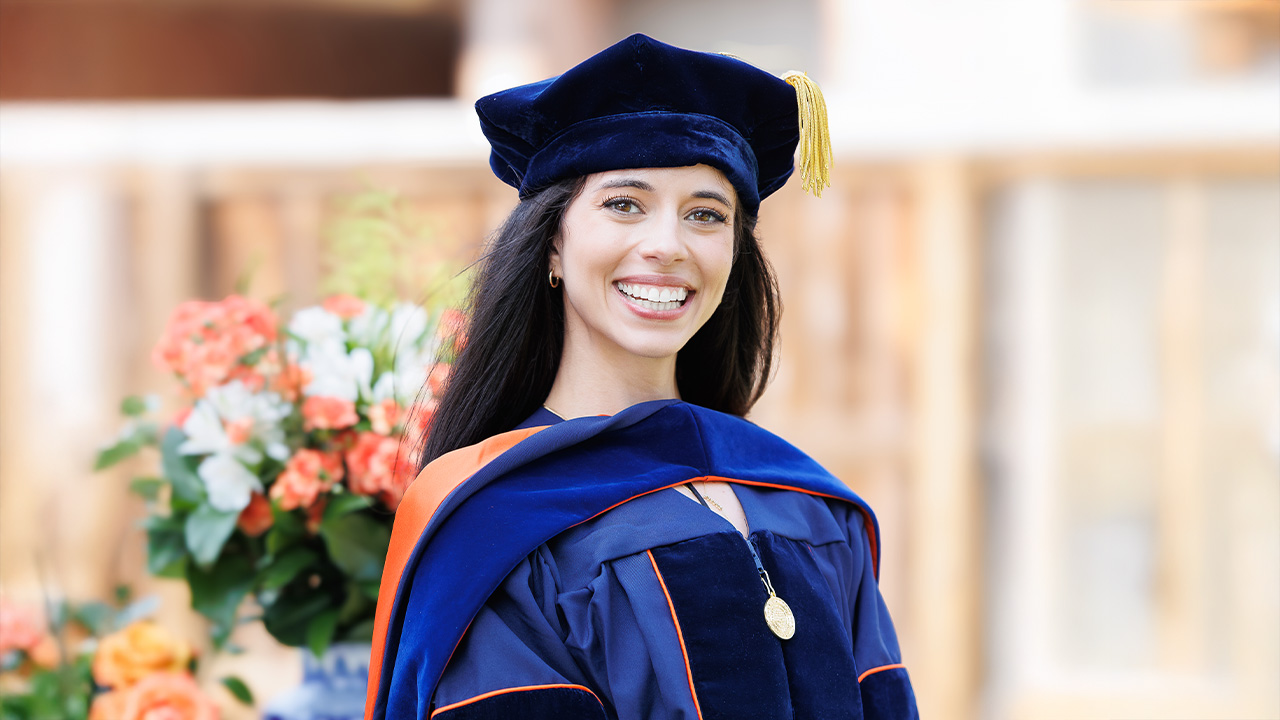Olivia smiles for the camera while wearing a graduation cap and gown