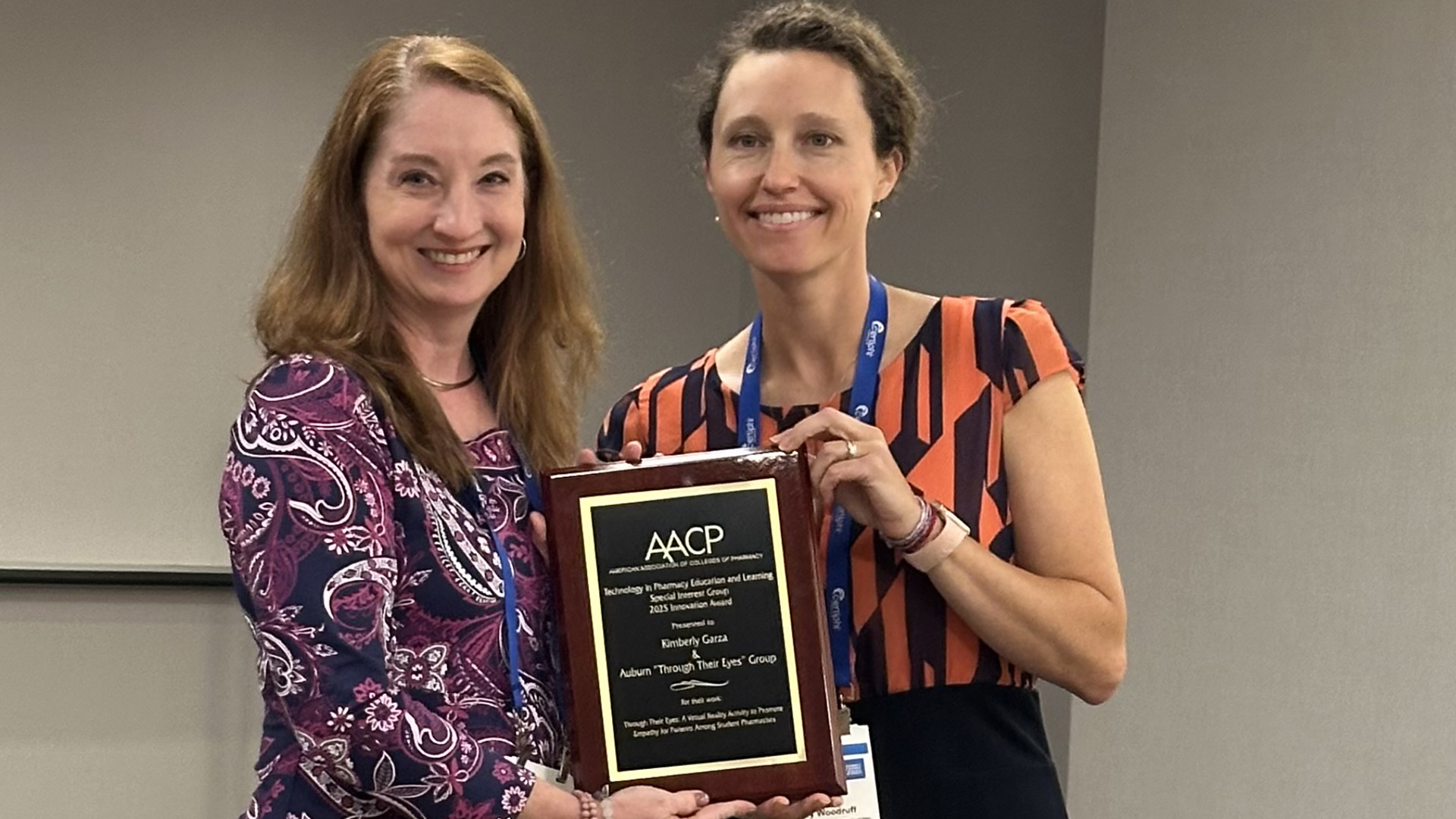 Two people stand with a plaque