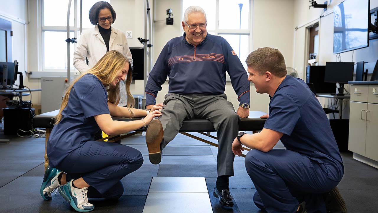 An Auburn faculty member and students work lead a community member through physical therapy exercises