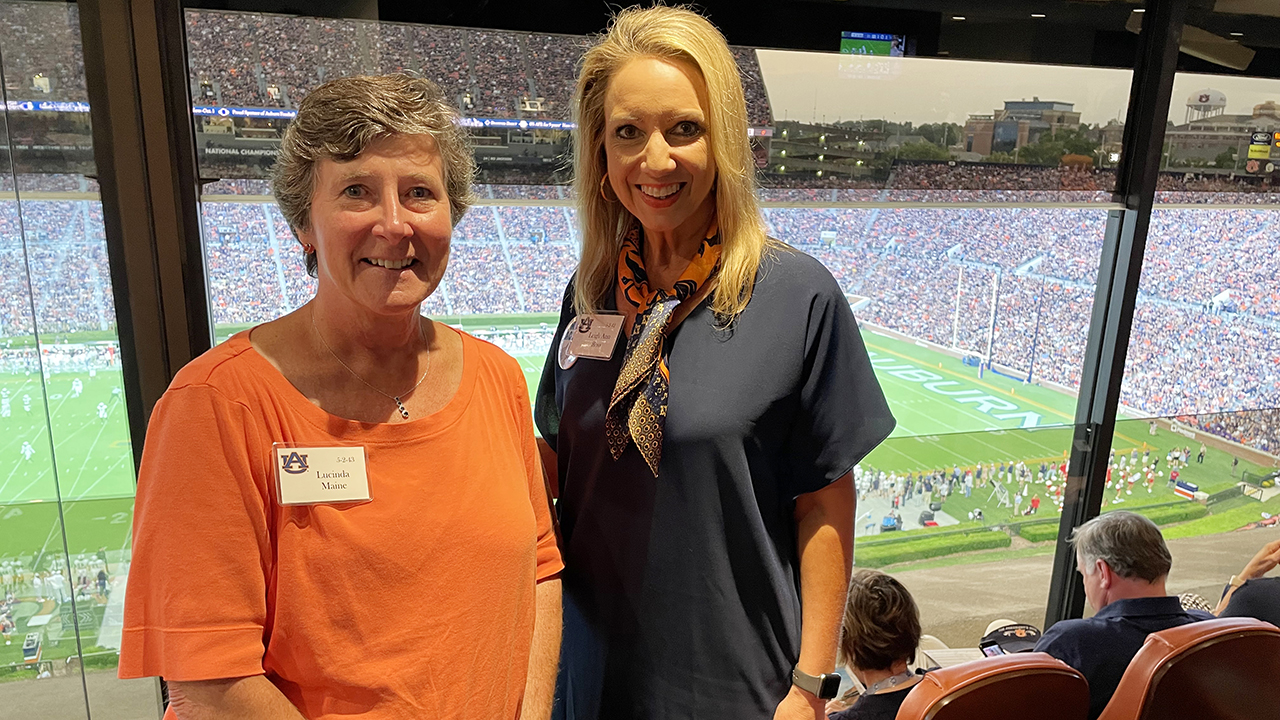 Lucinda Maine, 1980 pharmacy graduate, and Leigh Ann Ross, the Harrison College of Pharmacy dean, stand together at a football game in Jordan-Hare Stadium