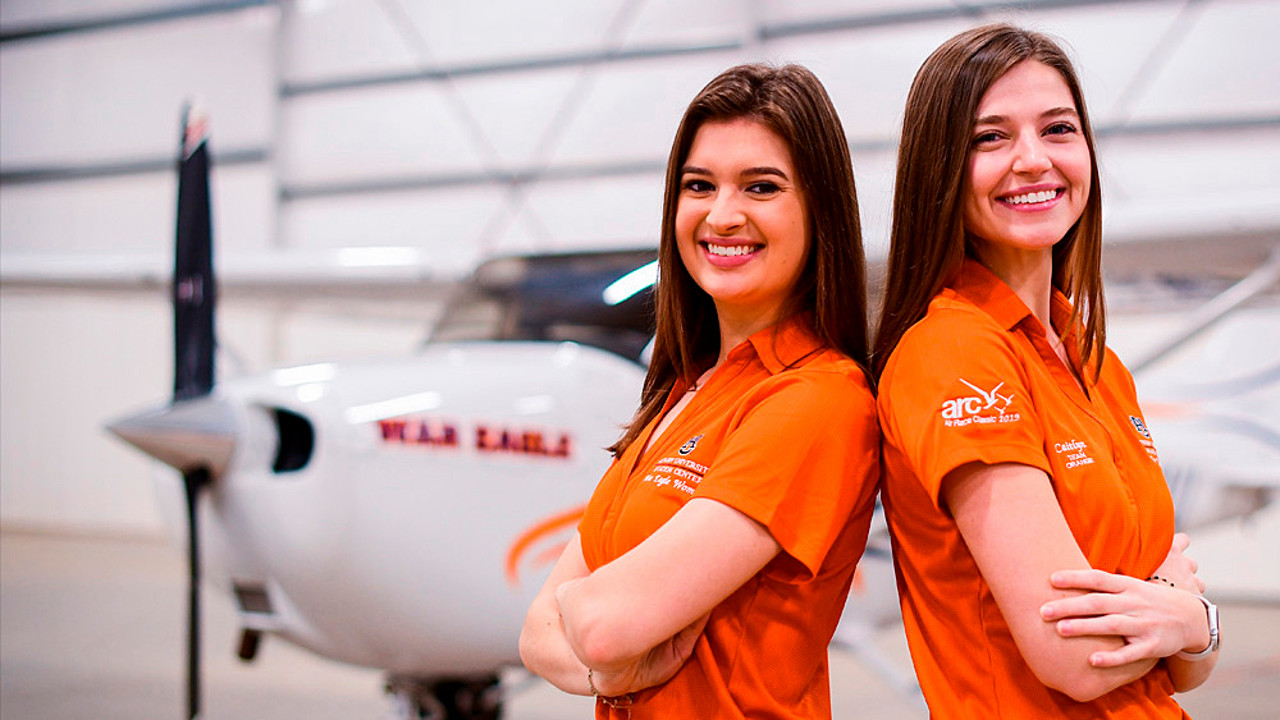 Kendall Higdon and Caitlyn Miller in front of an Auburn plane in a hangar