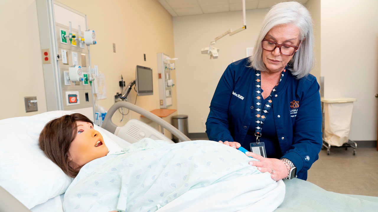 Karol Renfroe demonstrates nursing techniques with a pregnant manikin in the College of Nursing